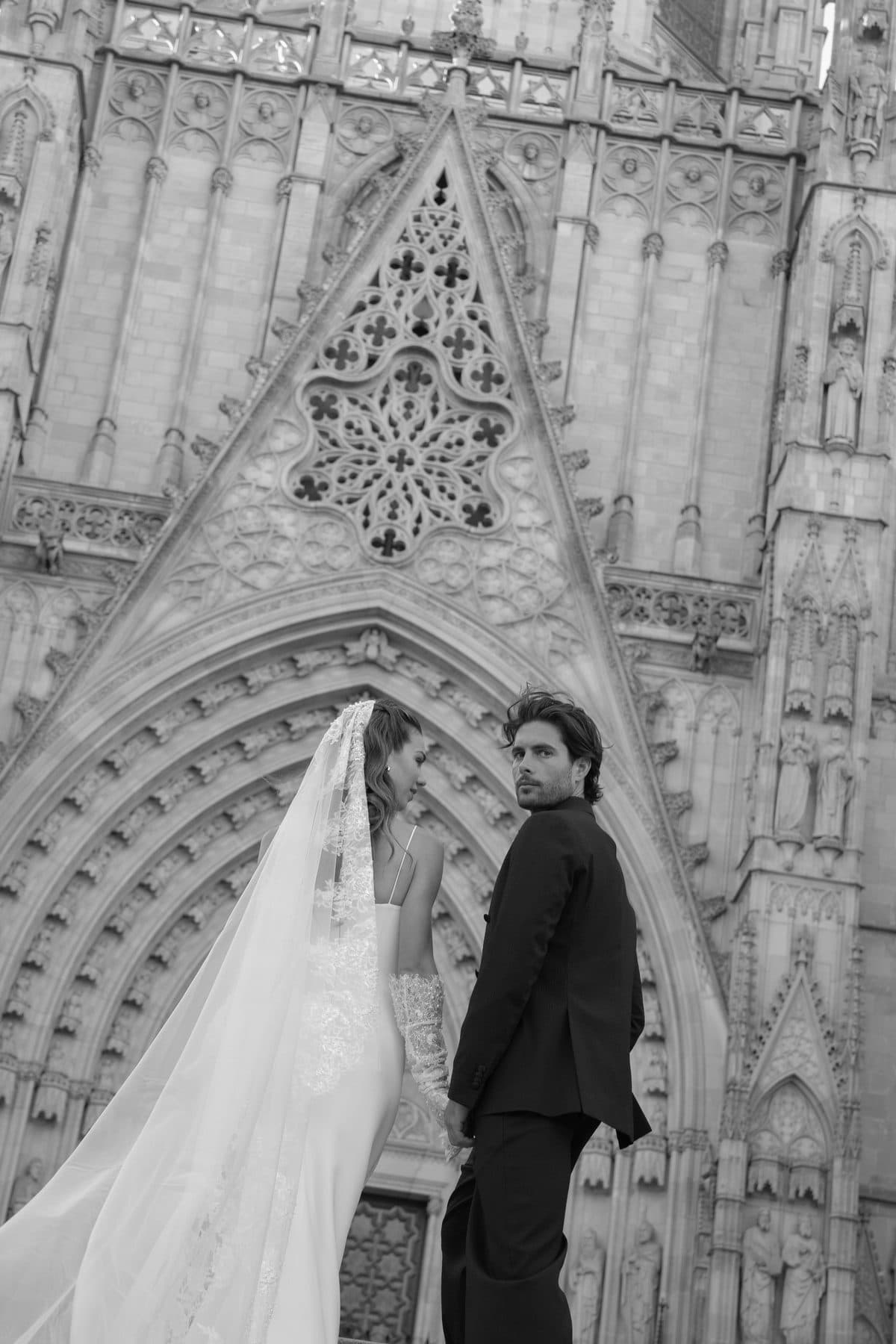 Black and white portrait of the couple, the groom glancing back at the camera