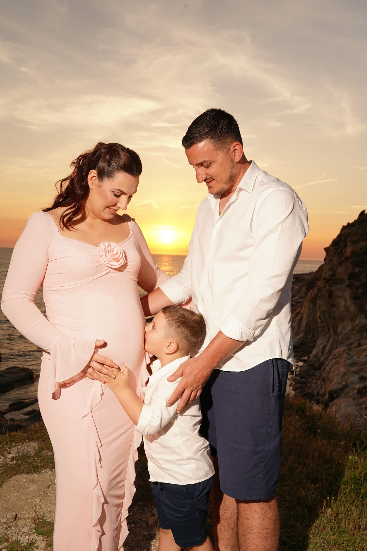 Family of three at sunset by the sea