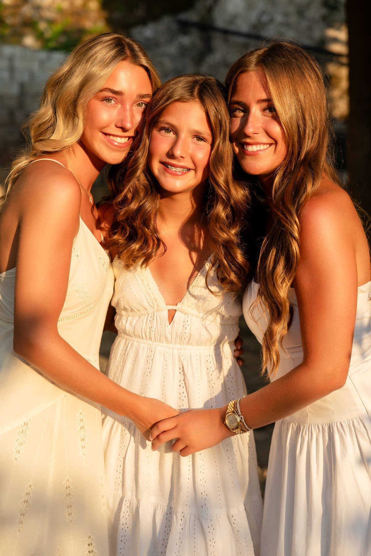 Three sisters in white dresses at golden hour