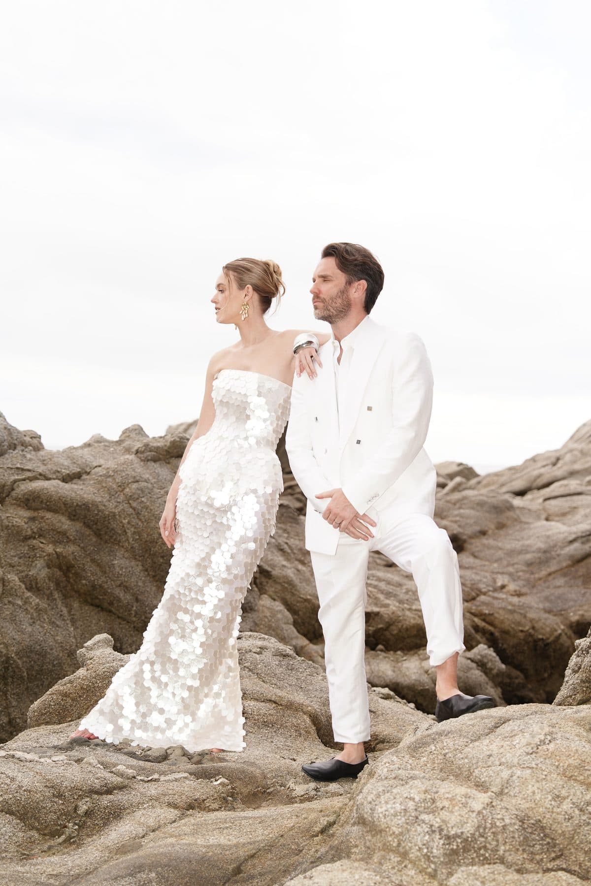 Bride leaning on the groom on the rocks in a sculptural pose
